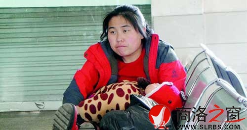 候車廳里，一位母親抱著睡著的孩子發呆